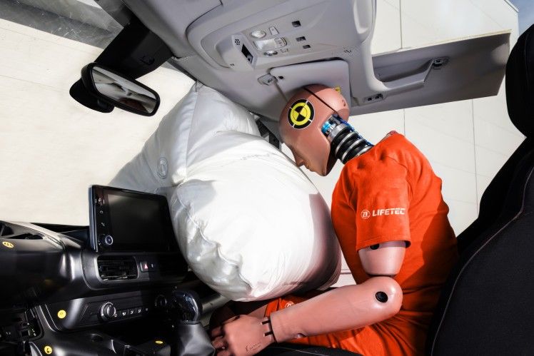 Crash test dummy with deployed airbag in car