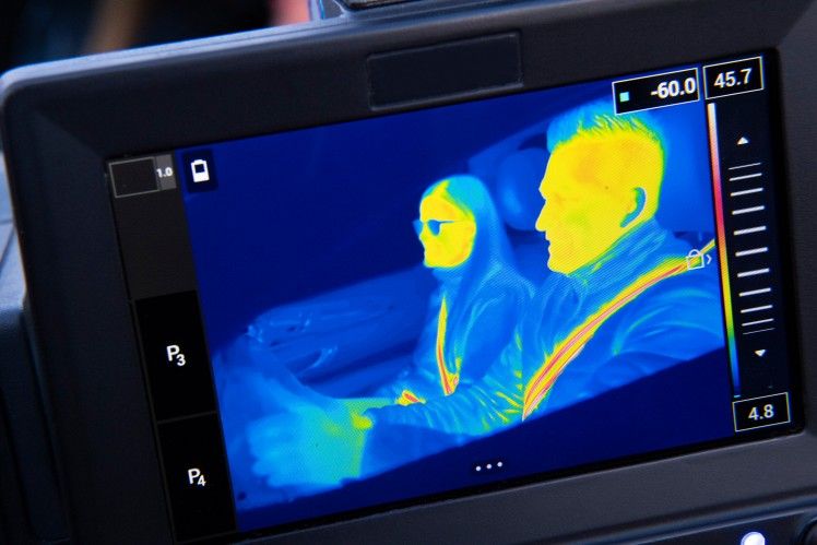Thermal image of two people in a vehicle, one wearing a seatbelt.
