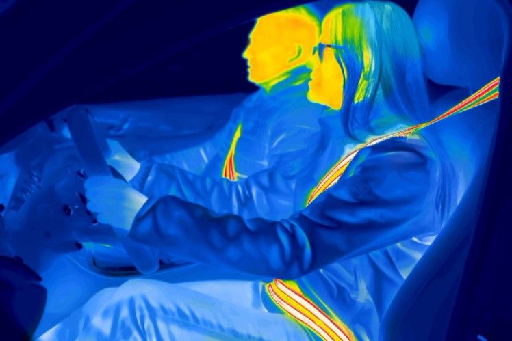 Thermal image of a person in a car seat with seatbelt