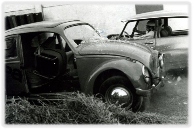 Damaged vintage car with open door and another vehicle in background