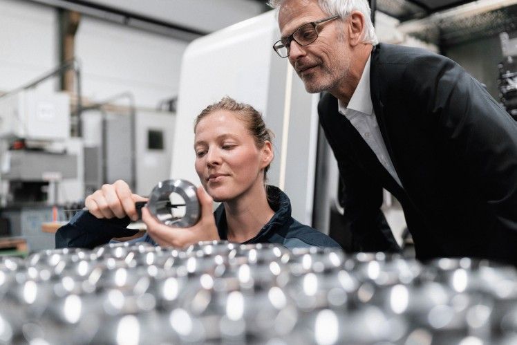 Engineer inspecting airbag component with supervisor in factory