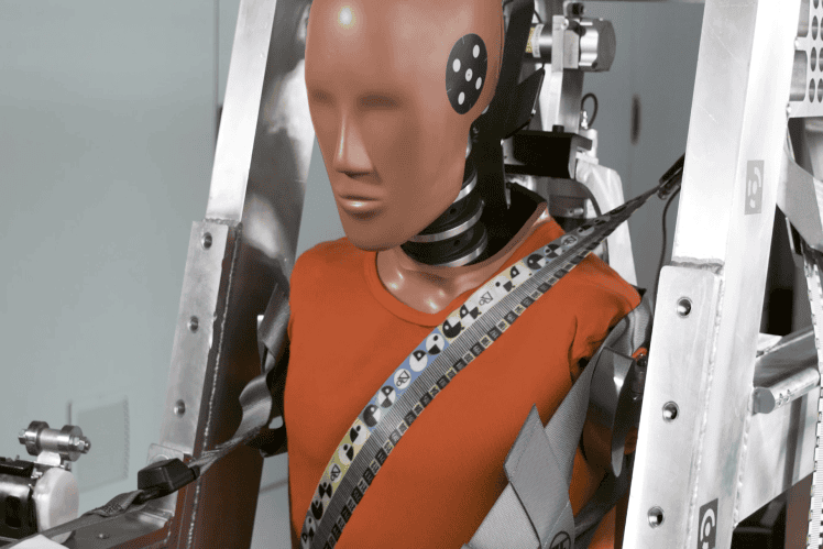 Crash test dummy secured with seatbelt in vehicle frame