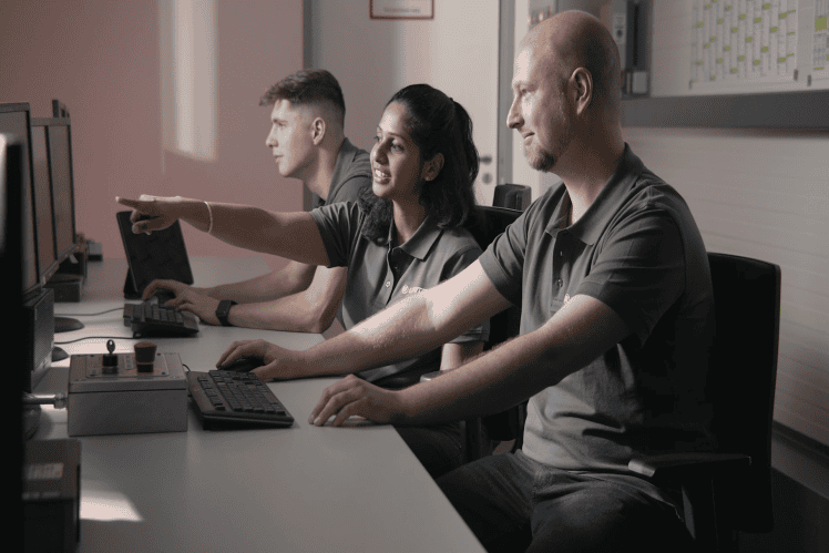 Three employees working at computers in an office