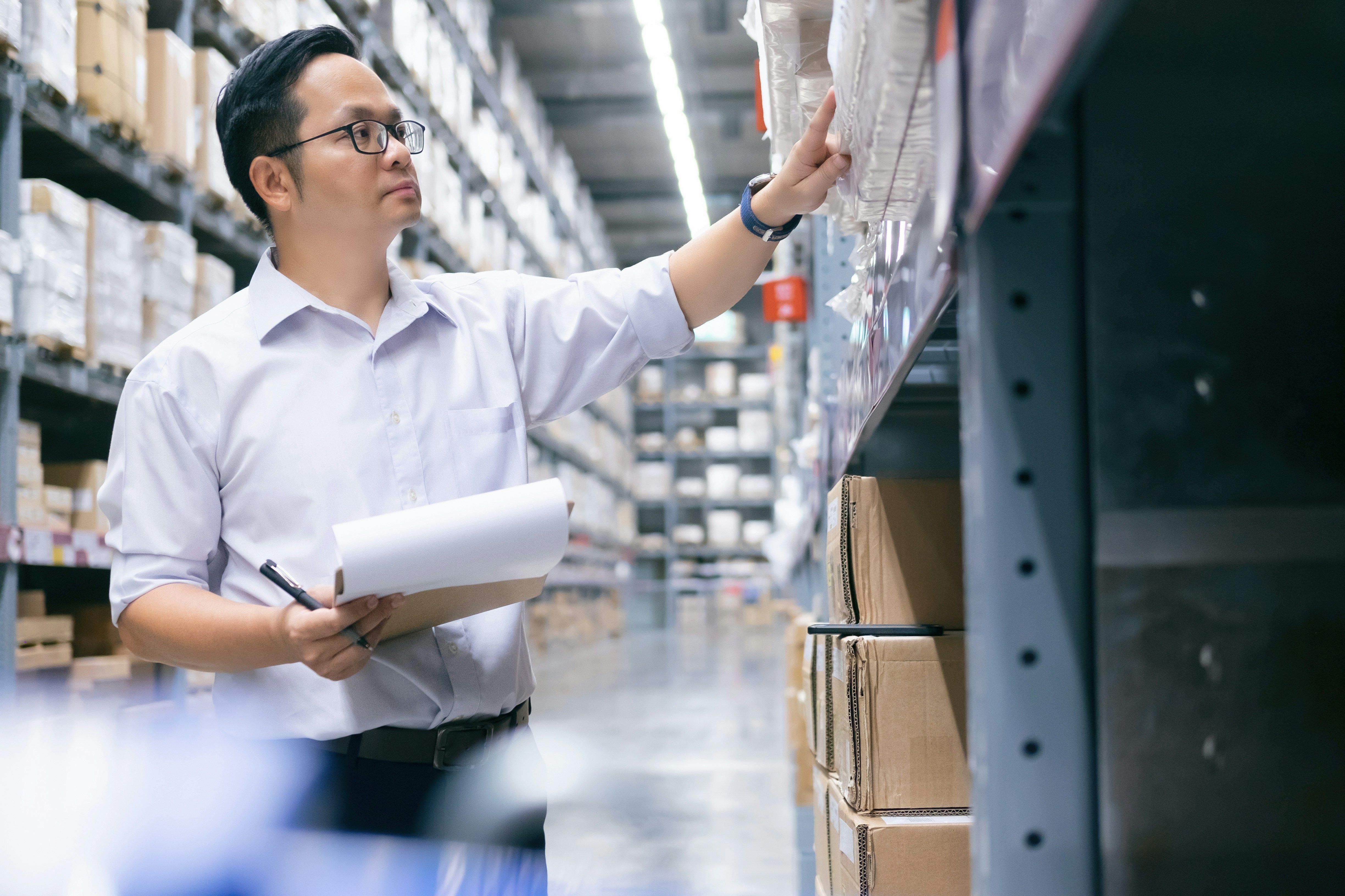 Man in warehouse checking inventory with clipboard