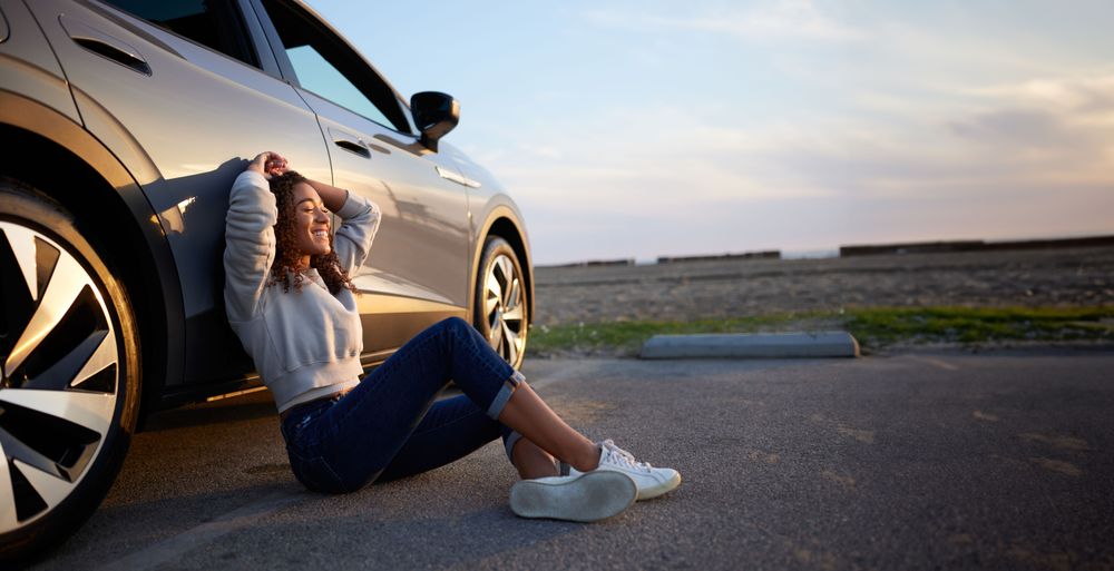 Woman leaning against car, smiling