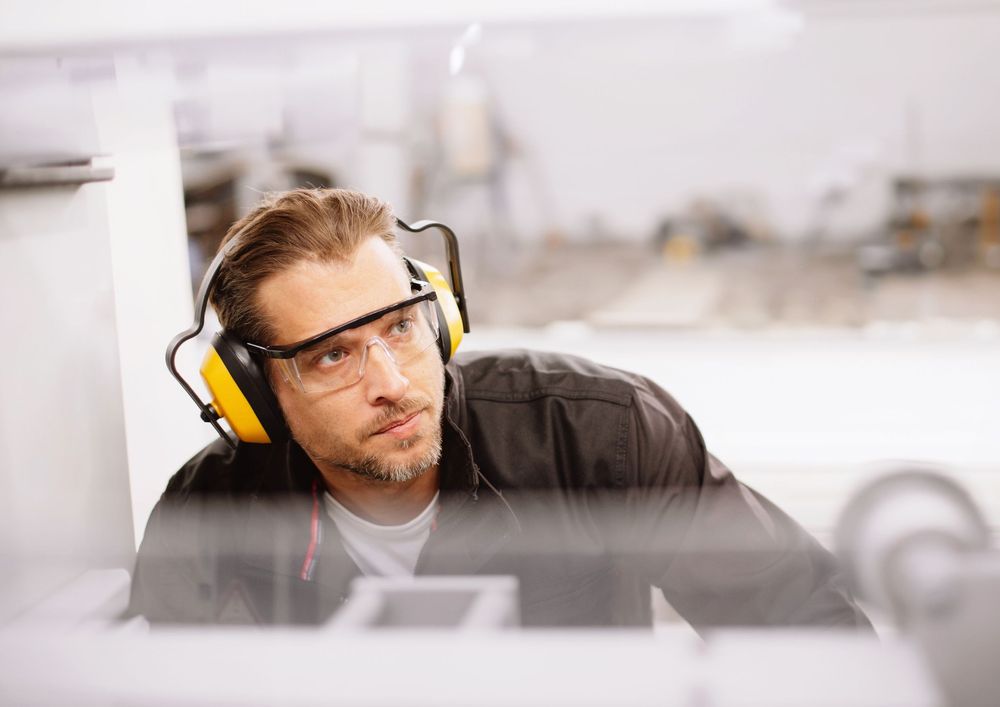 Worker wearing safety gear inspects vehicle part