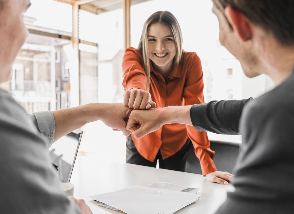 Team members fist bumping at a meeting table