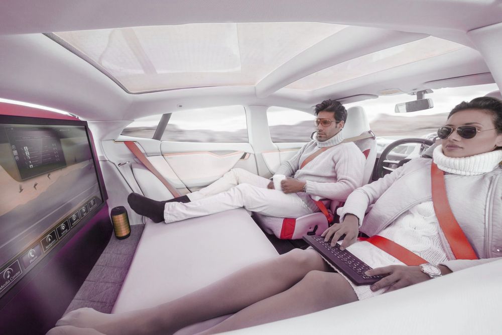 Man and woman using laptops in futuristic car interior