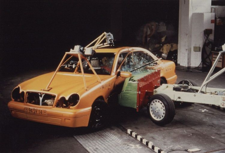 Orange car during crash test with safety equipment visible