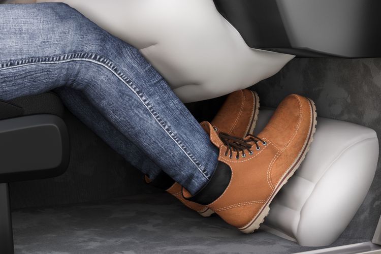 Person wearing jeans and brown boots resting feet on car dashboard