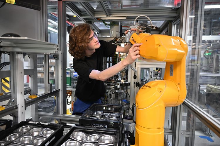 Worker adjusting industrial robot in manufacturing facility