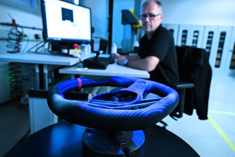 Engineer inspects steering wheel component under blue light