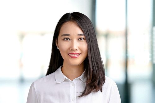 Young woman with long dark hair smiling in an office setting.