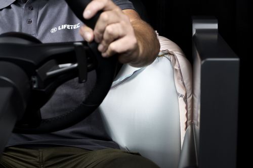 Person testing deployed airbag in vehicle
